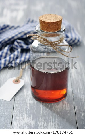 Maple syrup in glass bottle on a wooden background