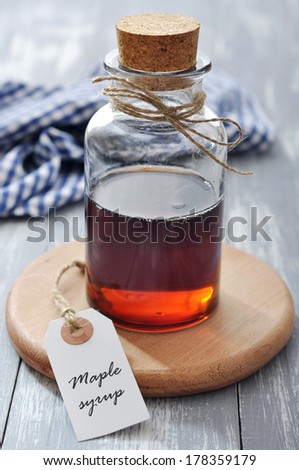Maple syrup in glass bottle on a wooden background