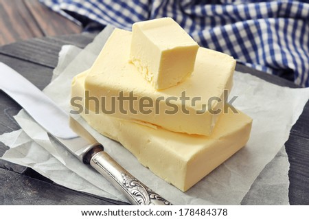 Fresh butter on wooden cutting board with knife closeup