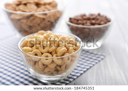 Various breakfast cereals in glass bowls on wooden background close-up