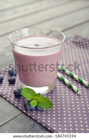 Blueberry smoothie with fresh berry and drink straws on wooden background