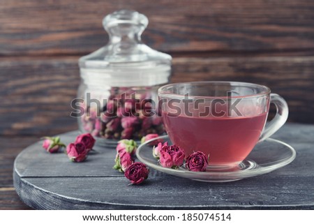 Tea rose flowers  in glass jar and tea on wooden background