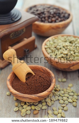 Ground coffee, green and roasted coffee beans  in wooden bowl closeup