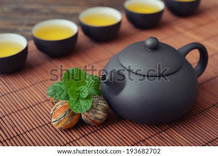 Green tea in cups with mint and teapot on bamboo mat