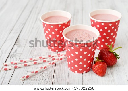 Milk shake with fresh berries and straws on wooden background