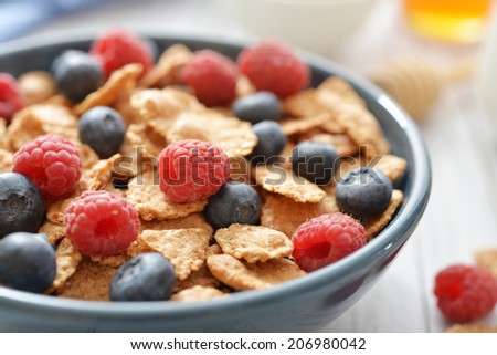 Whole-grain flakes in bowl with fresh berries on light background