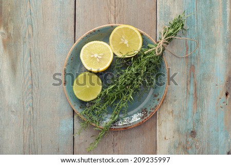 Fresh tarragon with lemon and lime on wooden background