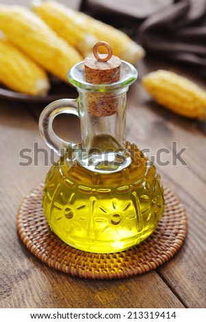 Corn oil in bottle with corn cobs on wooden background