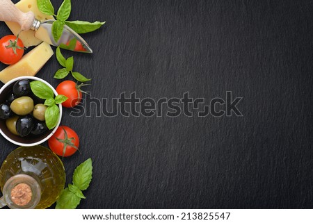 Ingredients of italian cuisine  - cherry tomato, basil, parmesan, olives  and olive oil - on dark background