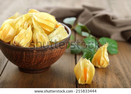 Physalis fruits in bowl closeup on wooden background