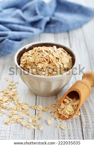 Oat flakes in bowl on white wooden background