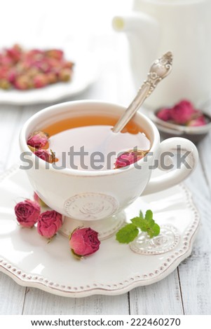 Tea rose flowers  and cup of tea on wooden background
