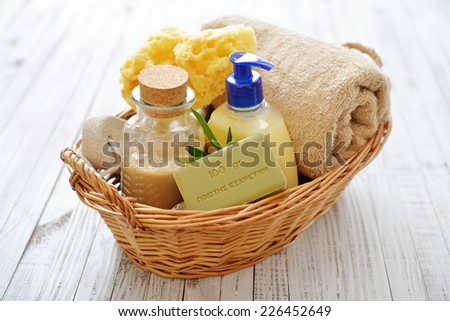Shower gel with  olive soap and bath towels in basket on wooden background. The words on soap translates as \