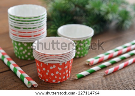 Cupcake cases with striped drink straws on wooden background