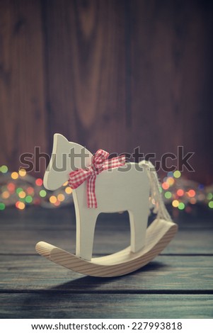 Toy horse with christmas lights on wooden background