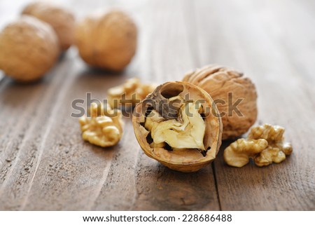 Walnut kernels and whole walnuts on rustic old wooden background