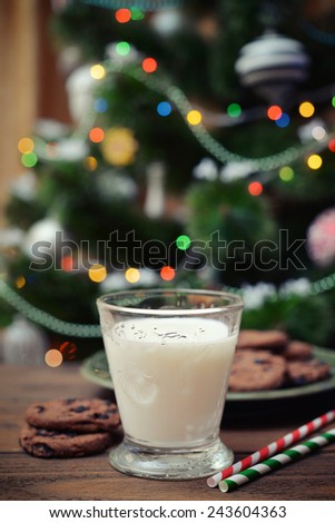 Milk and cookies for Santa Claus with drink straws on wooden tray