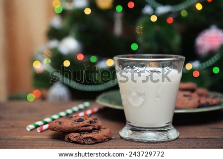 Milk and cookies for Santa Claus with drink straws on wooden background