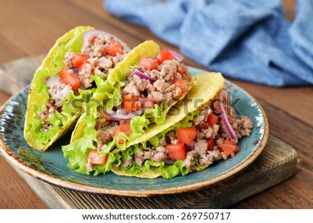 Mexican tacos with meat, onion and tomato on cutting board on wooden background