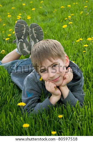 eight years old boy lying on dandelion meadow