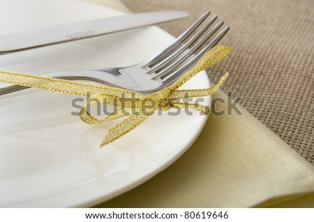 fork and knife on a white plate with a gold ribbon