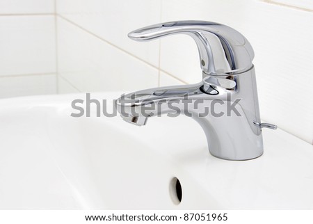 detail of a modern ceramic hand wash basin with chrome water mixer tap