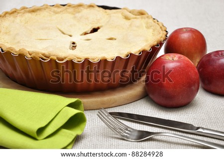 Home-baked apple pie, straight from the oven. Vintage enamel pie plate, fork and knife.