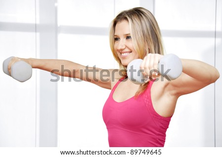 Pretty happy young woman exercising with free weights