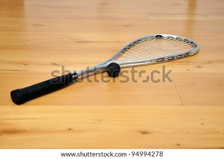 a squash racket and ball on the floor