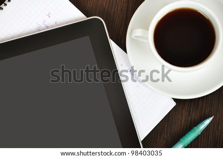 Workplace with  digital tablet, notebook, pen and cup of coffee on work table closeup