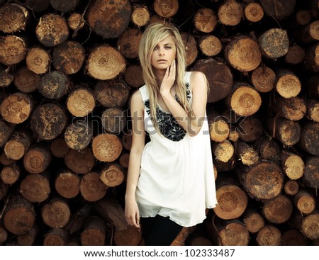 beautiful blonde posing in the background of logs