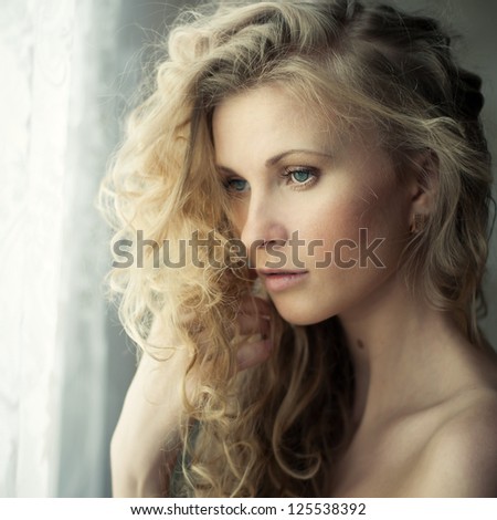 beautiful girl with lush hair near the window close up