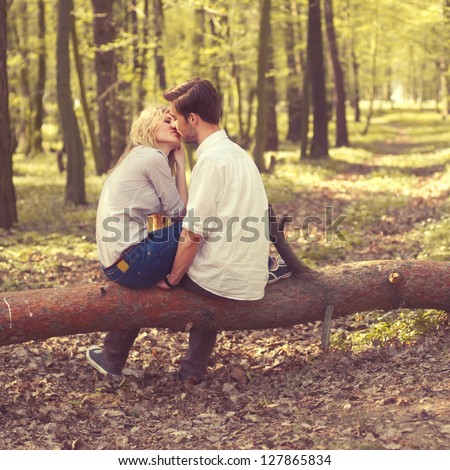 Happy Young Couple Kissing And Hugging, Sitting On A Tree