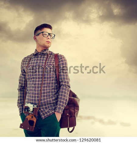 young, handsome man with a camera, dressed in the style of hipster