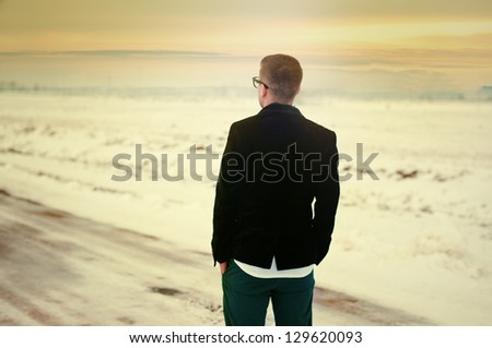sad young man on the road and looking at the sunset