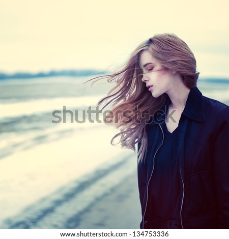 beautiful girl in windy conditions on the road in a field