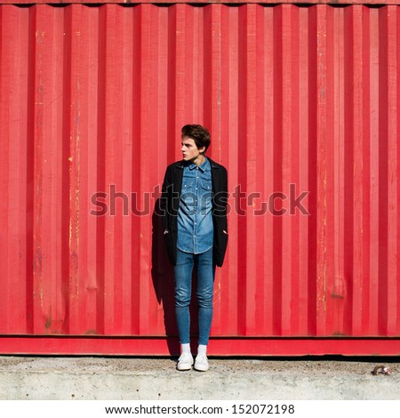 trendy hipster guy in a coat on a red wall