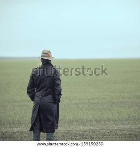 a man in a raincoat standing on the field