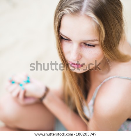 Beautiful young girl with bright nails on the beach in summer