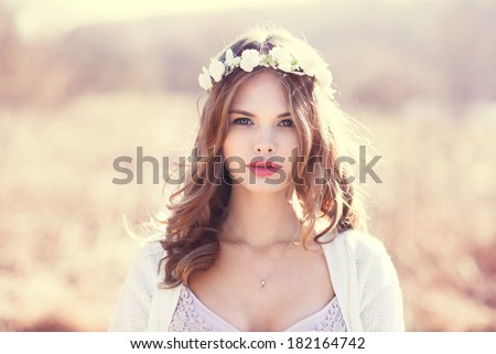 portrait of a sensual blonde with flowers on her head. photo done in the spring on a sunny day field