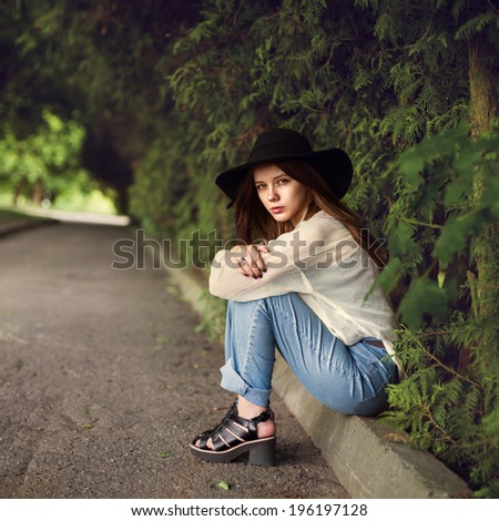 beautiful young woman in hat sitting in the park