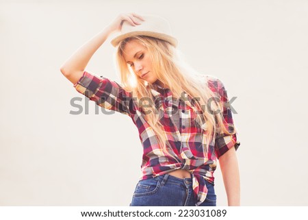 beautiful sexy blonde in a hat with long hair holds a hand a hat outside on a sunny day