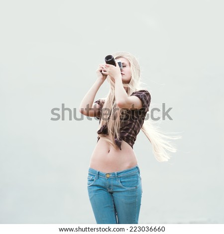 sexy girl with long hair and a vintage camera in a hat on the street on a sunny warm day