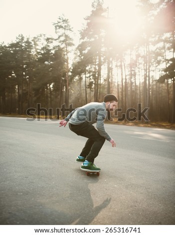 hipster boy skateboarder riding a skateboard in the park at sunset