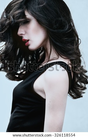 portrait of a beautiful young woman with sexy red lips and thick hair close-up outdoors on a windy day