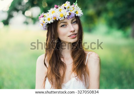 portrait of a beautiful sexy smiling girl with a wreath on his head in the spring park
