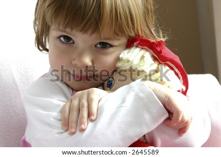 Little girl cuddling her doll with love.