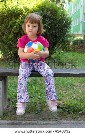 little, cute girl with colorful football outdoors