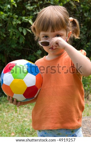 little, cute girl with colorful football, outdoors