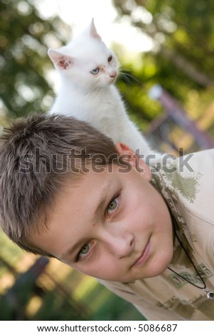 portrait of a boy with his cat climbing on his back